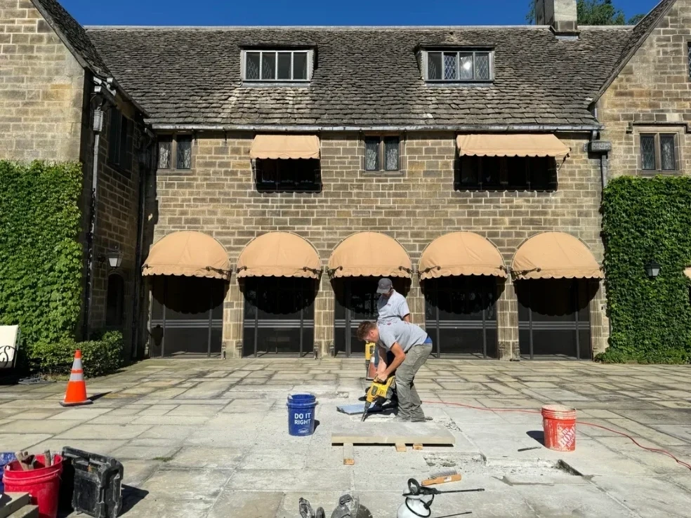 Crew performing masonry repair on historical stone building facade